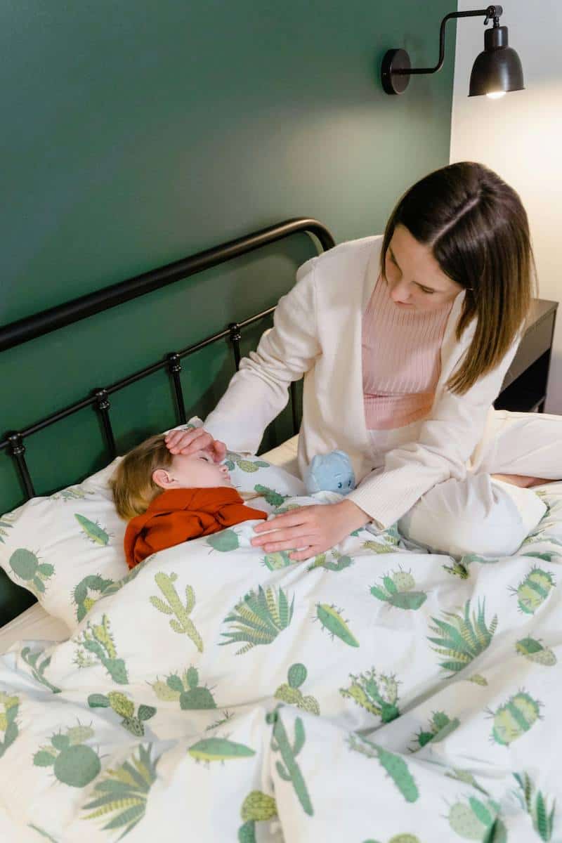 Caregiver gently comforting a young child resting in bed during child respite care.