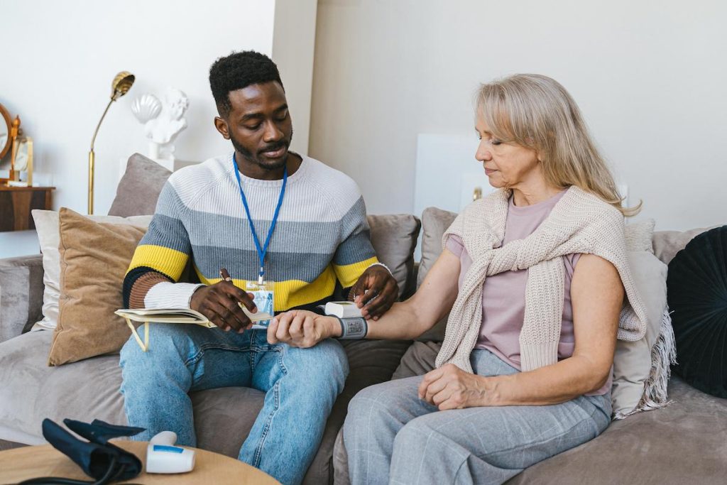 Caregiver measuring elderly woman's blood pressure during home visit in Saskatoon